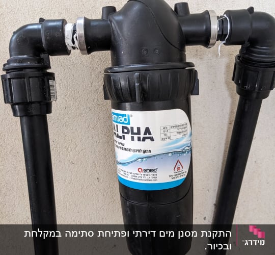 מסנן מים שחור עם צינורות מחוברים לקיר